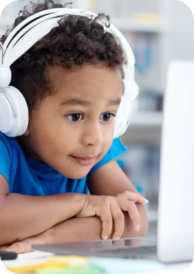 Child intently watches and listens to his laptop during his virtual tutoring session at home.