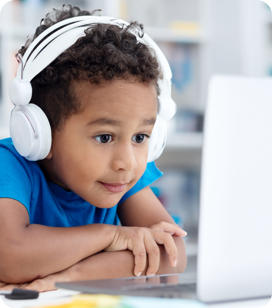 Child intently watches and listens to his laptop during his virtual tutoring session at home.