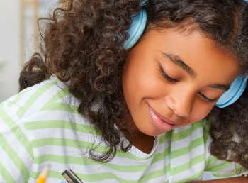 Girl at home wearing headphones working on live, virtual math lessons.