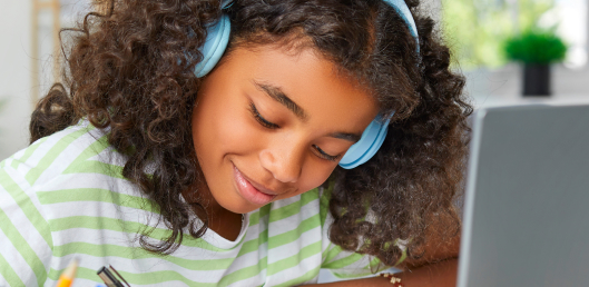 Girl at home wearing headphones working on live, virtual math lessons.