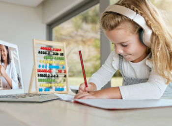 Young female student works independently during at her tablet with abacus.